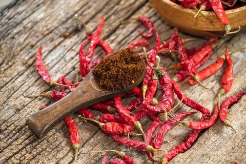 Dry red chilli and chilli powder in wooden bowl. red dried pepper on a dark.. Stock Photos