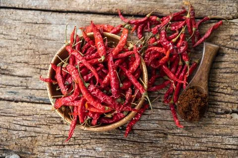 Dry red chilli and chilli powder in wooden bowl. red dried pepper on a dark.. Stock Photos