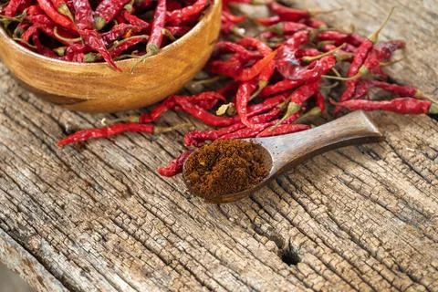 Dry red chilli and chilli powder in wooden bowl. red dried pepper on a dark.. Stock Photos