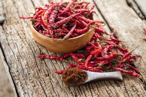 Dry red chilli and chilli powder in wooden bowl. red dried pepper on a dark.. Foto stock