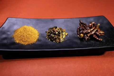 Dry red chilli, chilli flakes, red chilli powder on black platter isolated .. Stock Photos