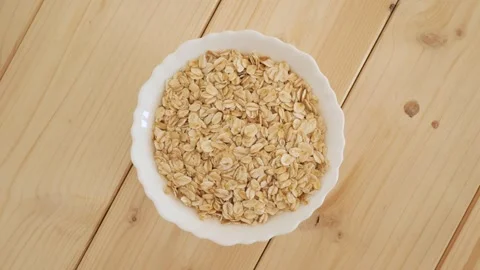 Dry rolled oats spinning in a white bowl Stock Footage 337011714