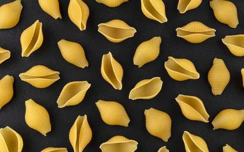Dry shell pasta pattern on black background, top view Conchiglie rigate. D... Stock Photos