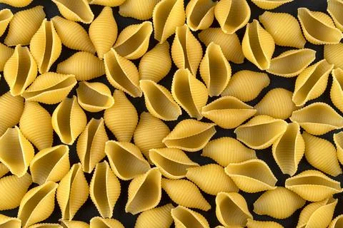 Dry shell pasta pattern on black background, top view Conchiglie rigate. D... Stock Photos