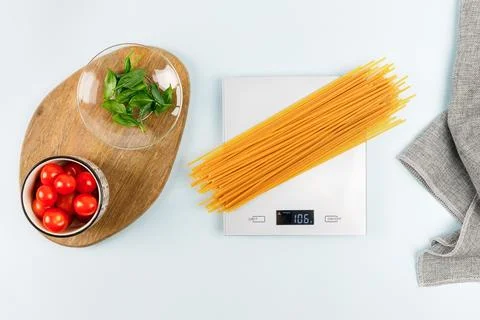 Dry spaghetti on gray digital kitchen scales. Flat lay. Pasta, italian cuisine. Stock Photos