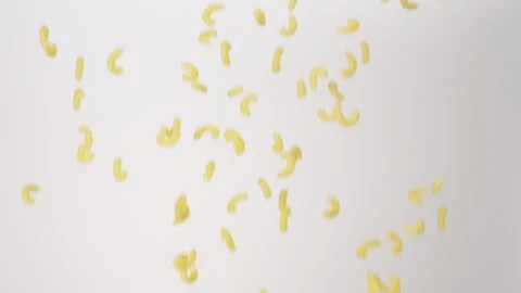Dry uncooked Elbow Macaroni Mac And Cheese Raining Slow Motion White Backdrop Stock Footage 336392374