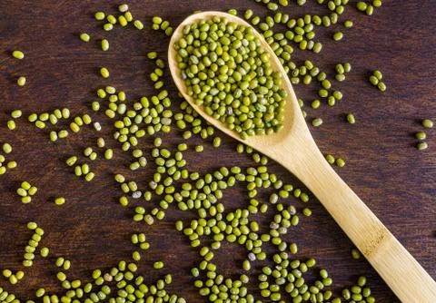 Dry uncooked mung beans in spoon on dark wooden background Stock Photos