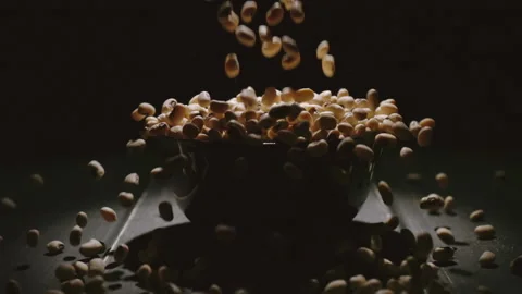 Dry white beans falling into a black bowl. Dark wooden surface. Slow motion. Stock Footage 133227053