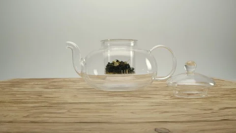 Dry white tea in transparent teapot, male's hand covers the pot with a lid Stock Footage 130049987
