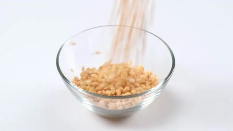 Dry yellow split peas falling into a glass bowl on white background Stock Footage 150329298
