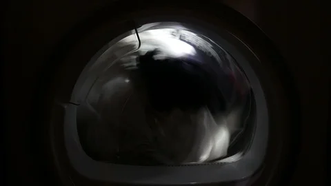 Dryer machine drying rotating swirl spin closeup porthole 4k light inside Stock Footage 105930020