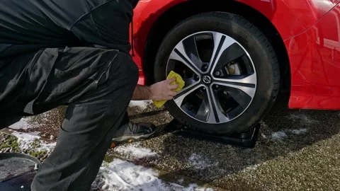 Drying alloy wheel and tyre Nissan Leaf with a yellow microfibre towel - Stock Footage 331632964