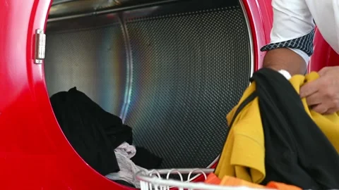 Drying clothes - putting clothes into a drying machine at the laundromat Stock Footage 252729278