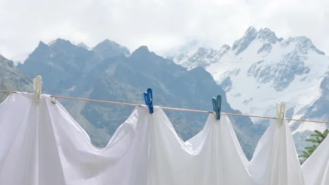 Drying fresh bed sheets on a clothesline against the mountains. Clean white Stock Footage 169706411