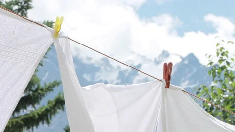 Drying fresh bed sheets on a clothesline against the mountains. Clean white Stock Footage 169706445