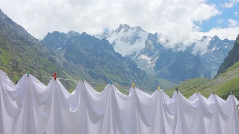 Drying fresh bed sheets on a clothesline against the mountains. Clean white Stock Footage 169706971
