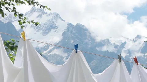 Drying fresh bed sheets on a clothesline against the mountains. Clean white Stock Footage 169707202