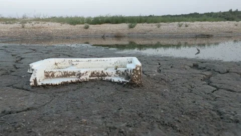 Drying lake with discarded garbage on the shore. Cracked earth. Stock Footage 94817239