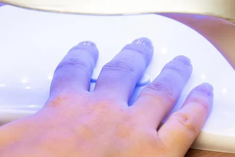 Drying nails after applying varnish in a special ultraviolet dryer Stock Photos
