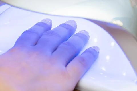 Drying nails after applying varnish in a special ultraviolet dryer Stock Photos