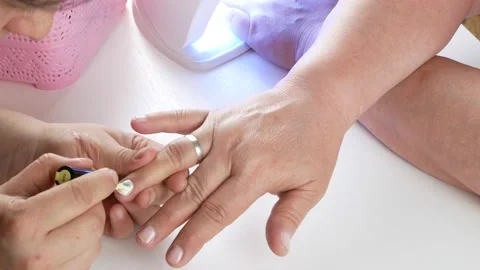 Drying in a UV lamp with LEDs. Master paints nails with varnish. Stock Footage 139697477