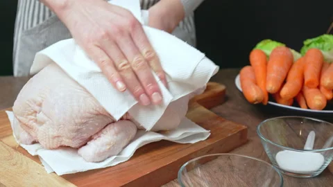 Drying a whole raw chicken before roasting with a paper towel on a wooden board. Stock Footage 145104287