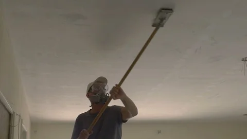 A drywall worker sanding a ceiling at a construction site Stock Footage 105383088