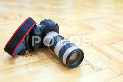 DSLR Camera with telephoto lens is on the parquet floor Stock Photos