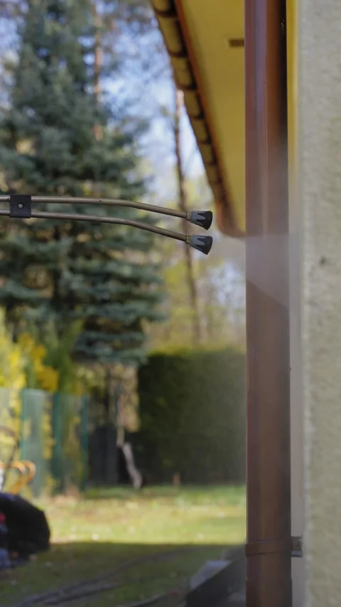 Dual nozzle facade washing machine spraying a house wall outdoors Stock Footage 336072968