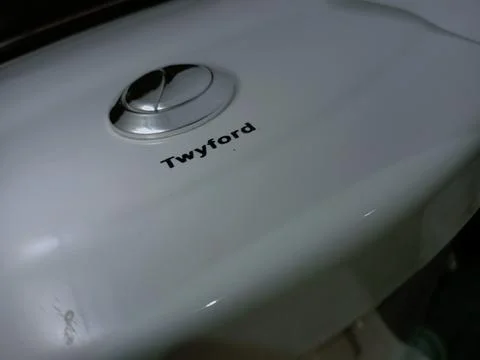 Dual silver push button on white Twyford water closet. Stock Photos