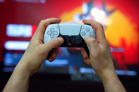 DualSense wireless controller for PlayStation 5 in classic white, held in m.. Stock Photos