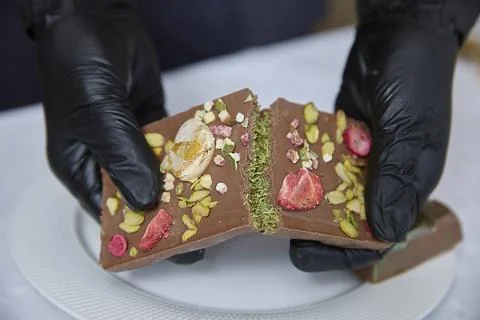 Dubai chocolate. Hands Present Artisinal Chocolate With Berries And Nuts Stock Photos
