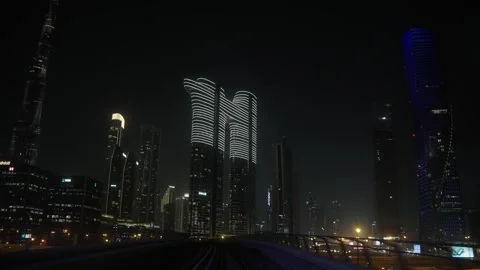 Dubai Metro train approaches covered station past Emaar in UAE Vidéo 344932035