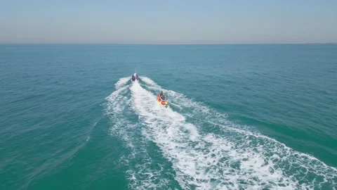 Dubai, UAE - 3 20 2023: A drone flies over a jet ski that pulls an inflatable Stock Footage 250228351