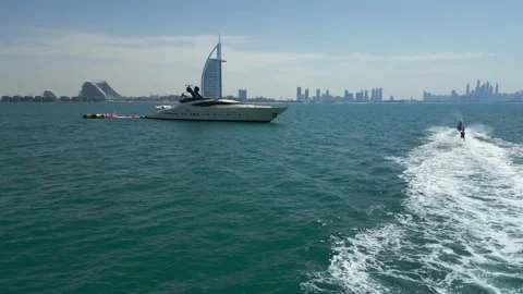 Dubai, UAE - 3 20 2023: A drone flies by on a jet ski that pulls a man on water Stock Footage 251558220