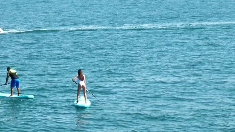 Dubai, UAE - 3 20 2023: A drone flies over a pair of young people sailing on SUP Stock Footage 255723670