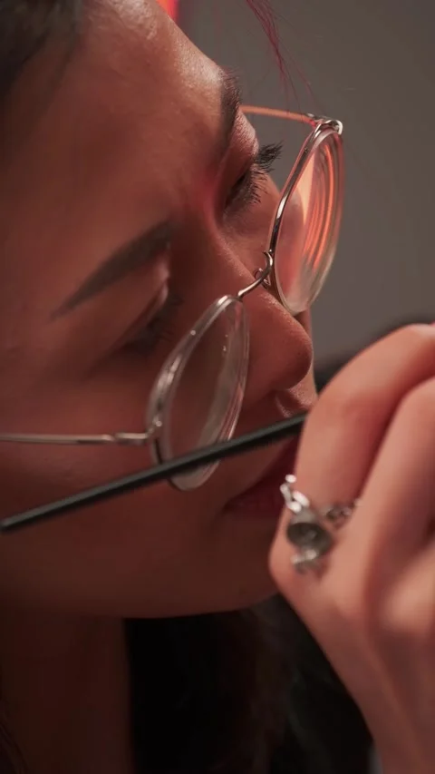 Dubai, UAE - 6 10 2023: Makeup artist in glasses working with young model in Stock Footage 340398151