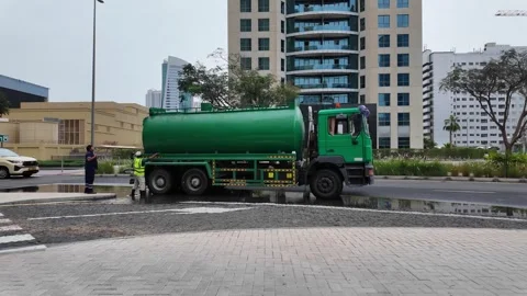 DUBAI, UAE - MAY 14, 2026: Municipal workers using water tankers and pumps .. Stock Footage 334921299