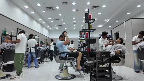 DUBAI, UAE - MAY 15, 2026: Professional barbers providing haircuts and bear.. Stock Footage 334929970