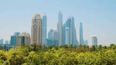 Dubai, UAE - May 5, 2024: Modern Dubai skyline with tall skyscrapers behind lush Stock Footage 287609227