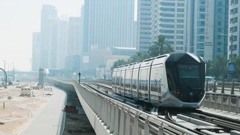 Dubai, UAE - May 5, 2024: Dubai tram passing through modern skyscrapers and Stock Footage 288041799