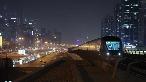 Dubai, UAE - October 28, 2025: Subway train traveling at night alongside a .. Stock Footage 333514194