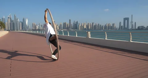 Dubai, UAE, young man is doing wheel gymnastics on The Palm Jumeirah, 4k Stock Footage 151523607
