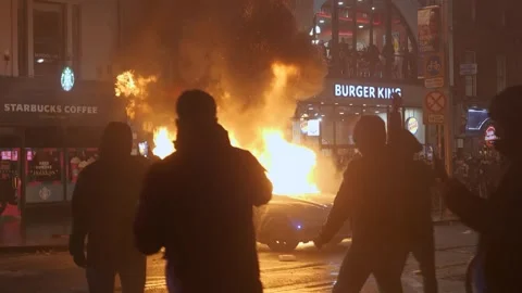 DUBLIN RIOT 2023: protesters chant "get them out" as Garda car burns Stock Footage 346228598