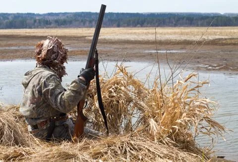 Duck hunter sitting next to the blind of reeds Stock Photos