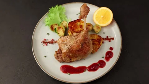 Duck leg confit with Brussels sprouts, baked potatoes, thyme, orange and sauce. Stock Footage 330476834