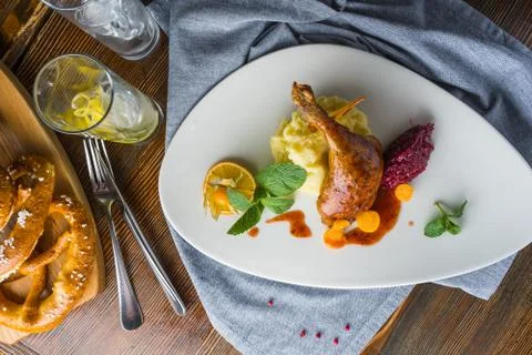 The duck leg on a rustic table in a cozy pub Stock Photos
