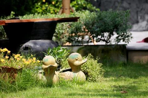 Duck statue put on field among flower plant with sunlight Stock Photos