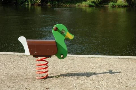 Duck swing on playground on river bank Stock Photos