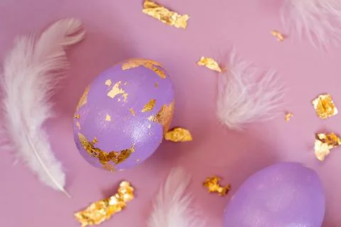 Dued Easter egg, violet or very peri with golden foil and feathers on violet Foto stock